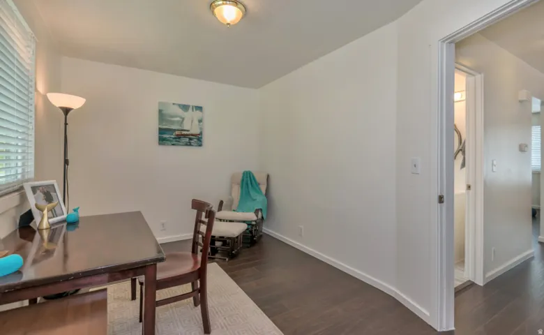 White walls, dark wood-finish flooring, and a window with horizontal blinds
