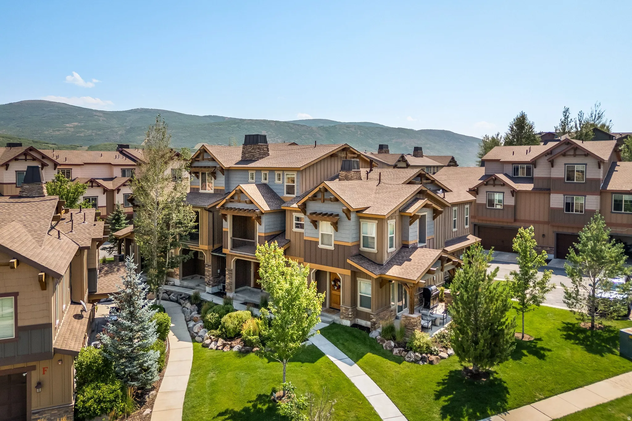 Multiple-story residences with varied exterior finishes, gabled roofs, stone accents, and covered porches