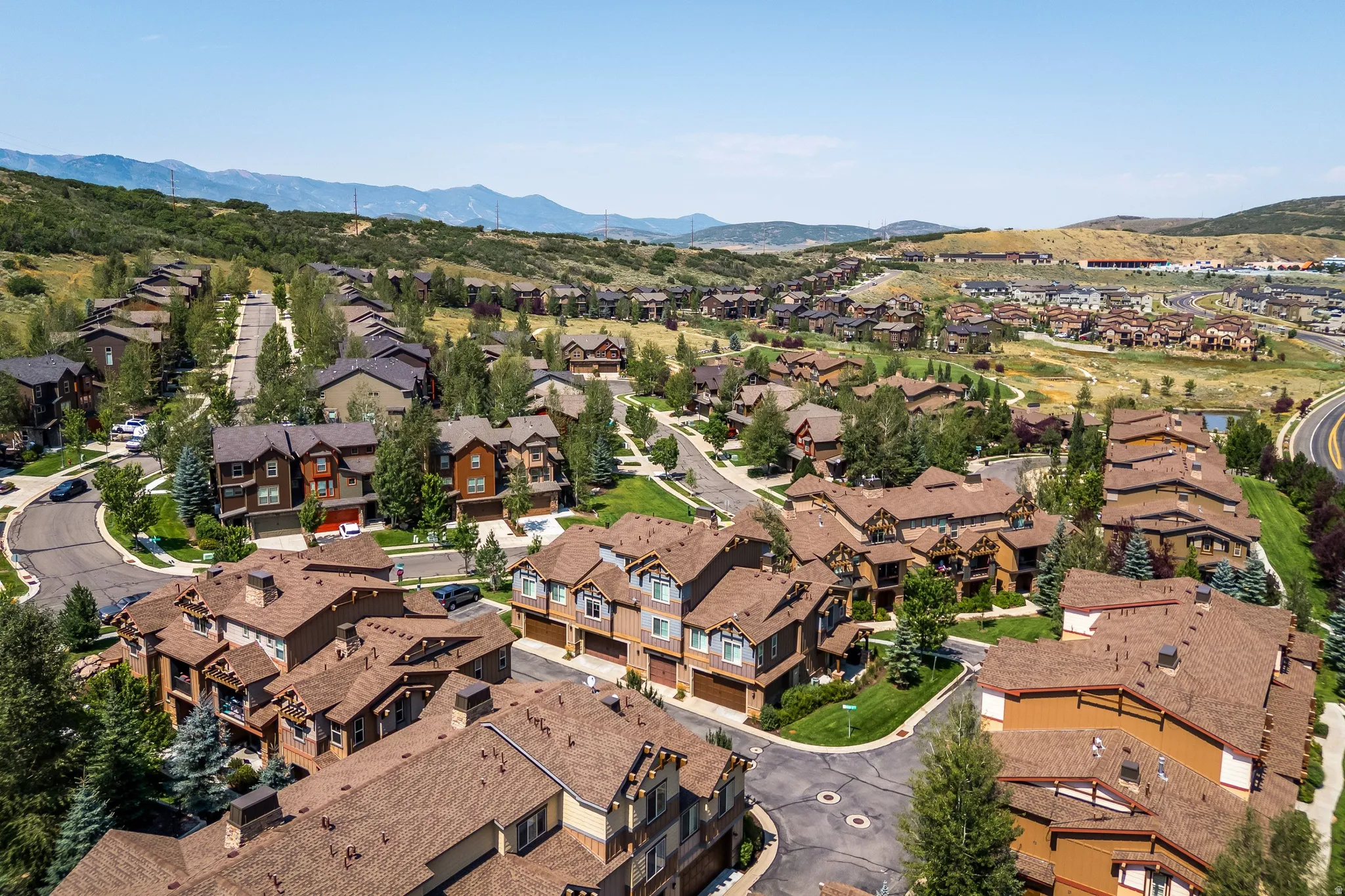 Expansive residential community with varied architectural styles, mature landscaping, paved roads, and mountain backdrop