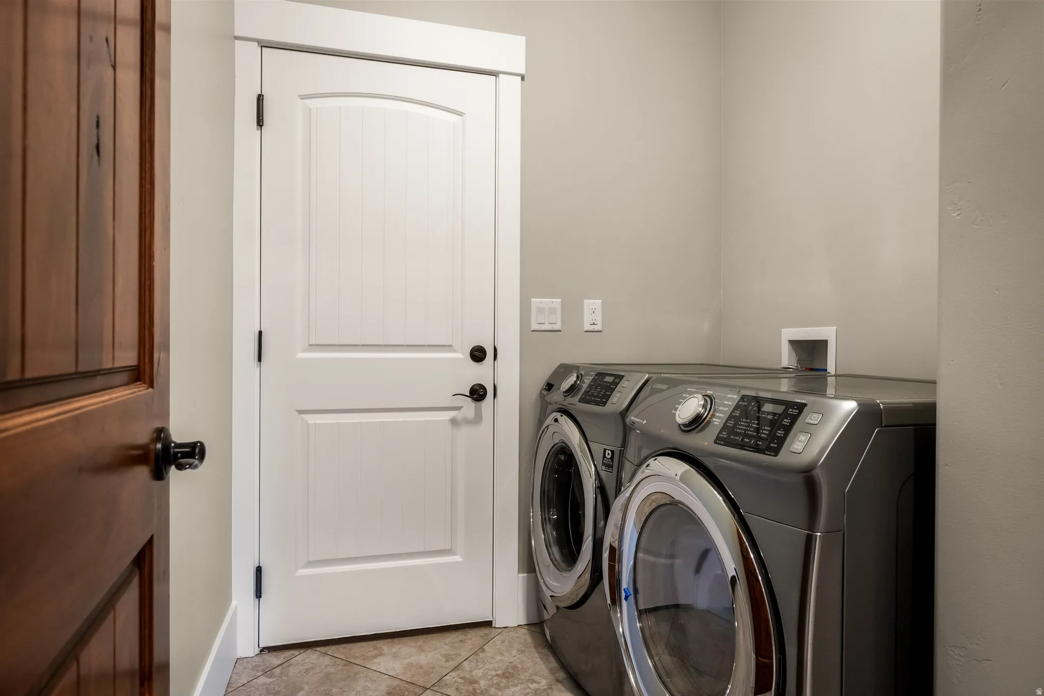 Tiled flooring, white trim, and a white paneled door with black hardware