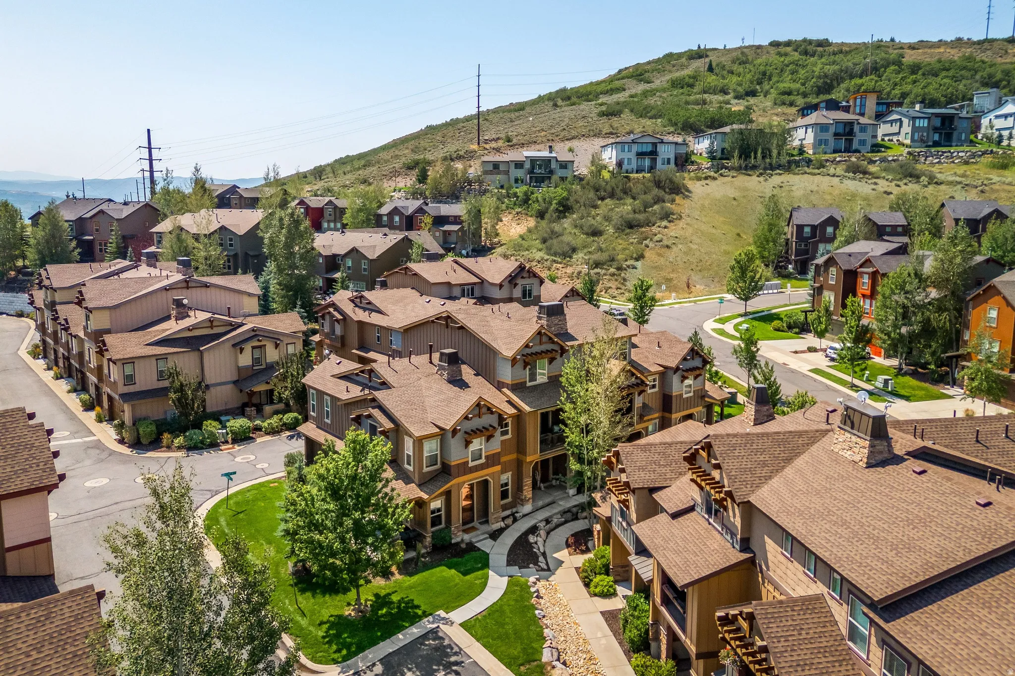 Hillside community featuring residential structures with brown shingle roofing, visible street infrastructure, and green spaces