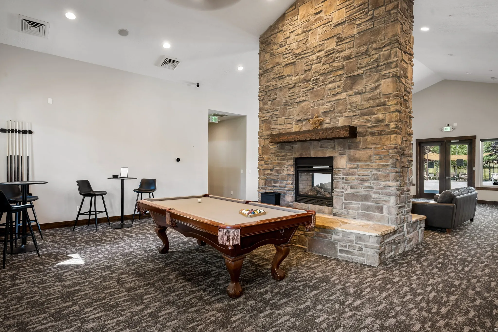 Stone-finish fireplace with a substantial hearth, vaulted ceiling, and recessed lighting