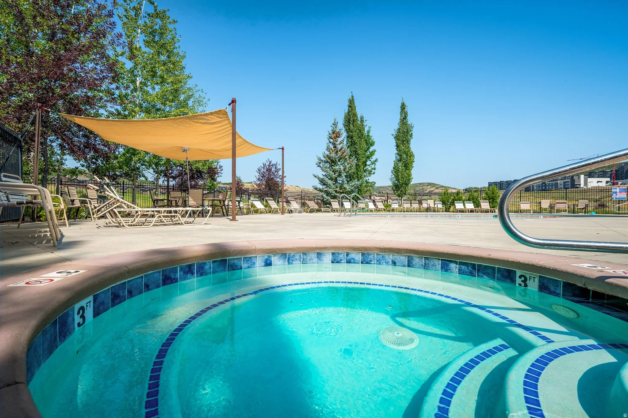 Spa with blue tile detailing, surrounding concrete decking, and partial shade canopy
