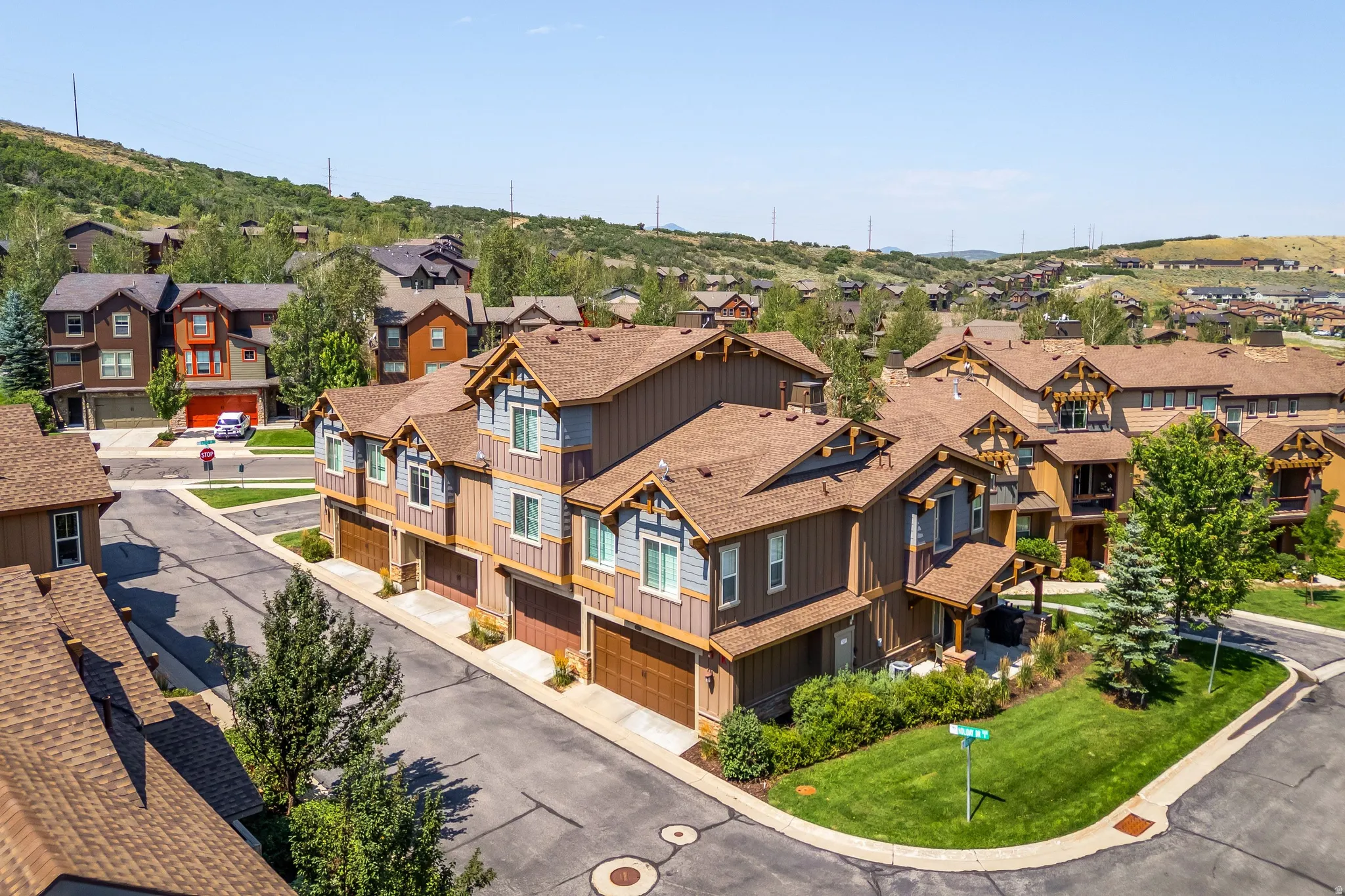 Townhome architecture featuring multi-gabled roofs, wood-look siding, and individual garage access