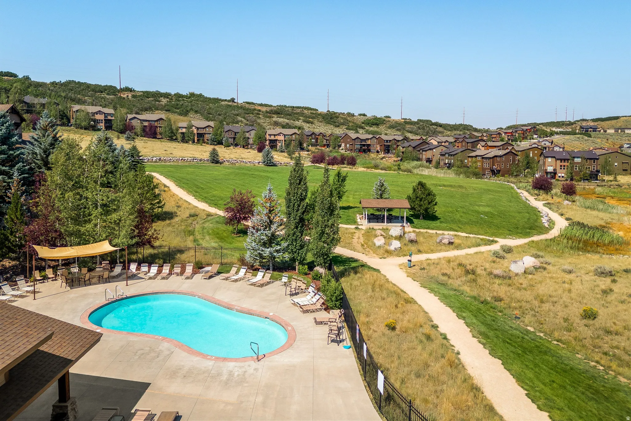 Resort-style swimming pool with surrounding patio, landscaped green spaces, and a covered gazebo