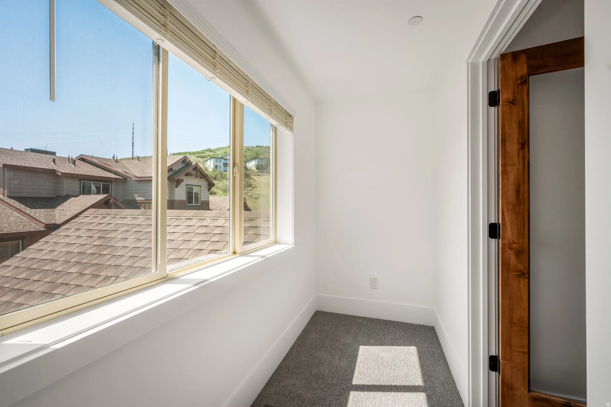 Bright interior space with large windows, white walls, and gray carpeting