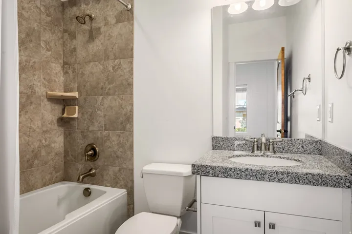 White vanity with dual-door cabinetry, a drop-in sink, and granite countertop