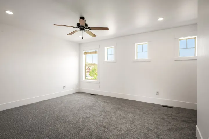 Recessed lighting, ceiling fan, white trim, multiple windows, and gray patterned carpeting