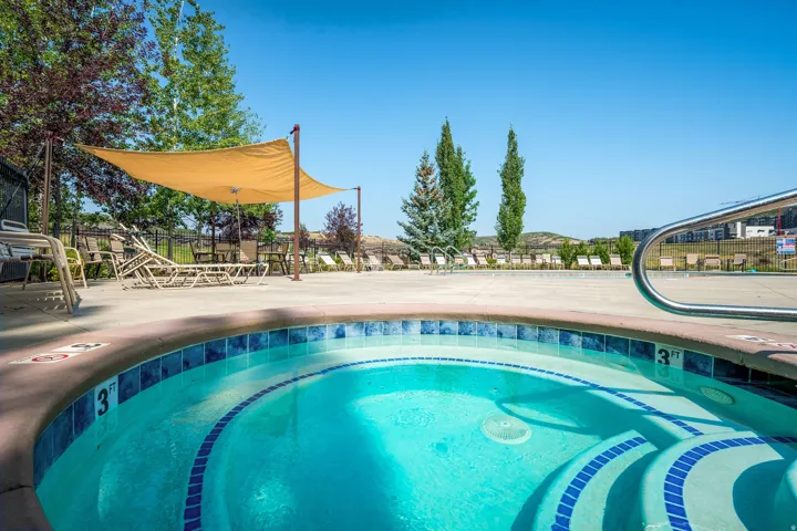 Spa with blue tile detailing, surrounding concrete decking, and partial shade canopy