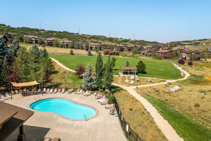 Resort-style swimming pool with surrounding patio, landscaped green spaces, and a covered gazebo