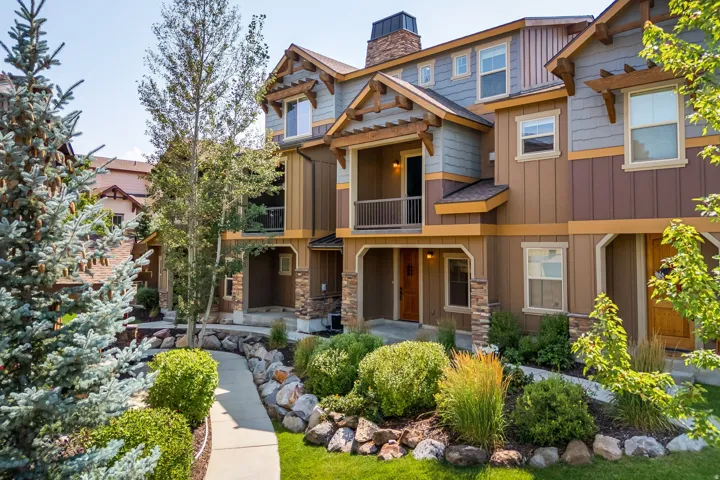 Multi-level townhome exterior with mixed siding, stone accents, and a front balcony