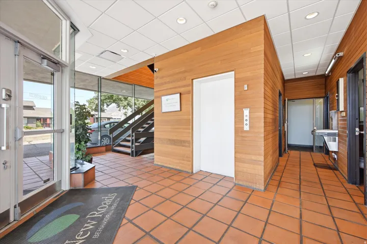 Tiled flooring, wood-panel walls, commercial-grade glass doors, built-in elevator, and exposed staircase