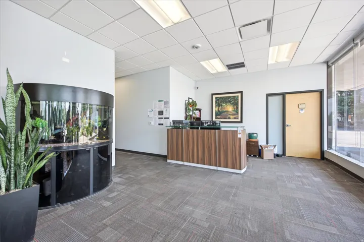 Reception area featuring a wood-finish desk, recessed ceiling lighting, and a built-in curved aquarium