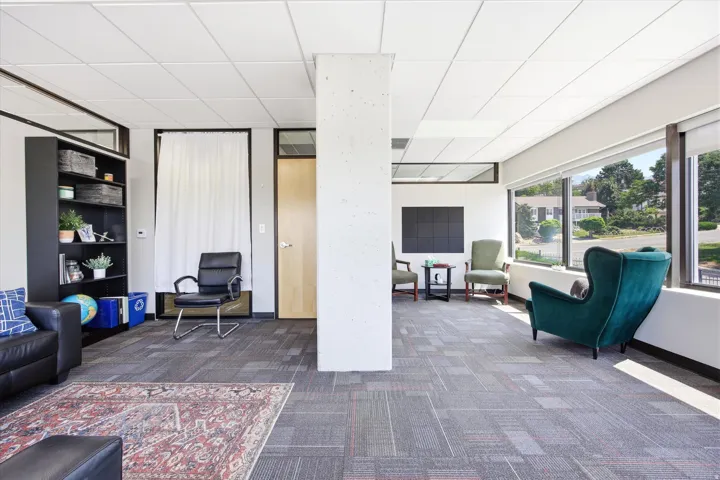 Expansive room featuring wall-to-wall carpeting with a geometric pattern, large window banks, and a drop ceiling