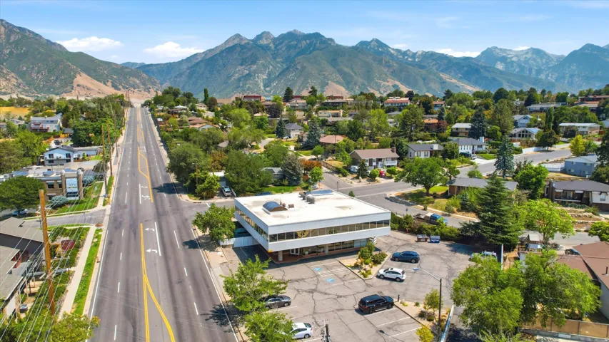 Commercial property featuring a white exterior with extensive window lines, a flat roof, and an asphalt parking area