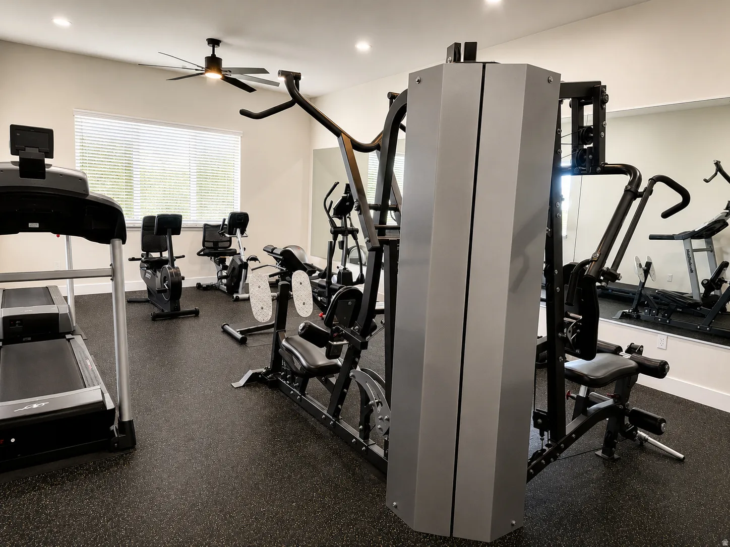 Dedicated fitness space featuring rubber flooring, a ceiling fan, and a large window