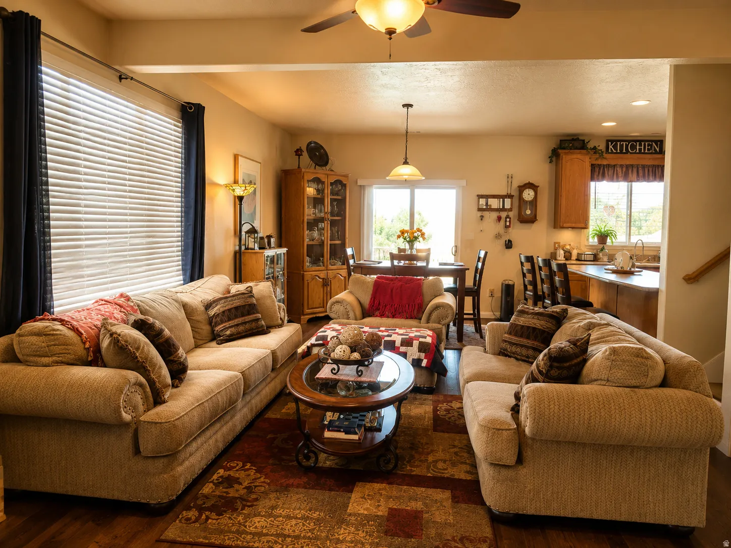 Open-concept common area featuring LVP flooring, a ceiling fan with integrated lighting, and a kitchen with wood cabinetry