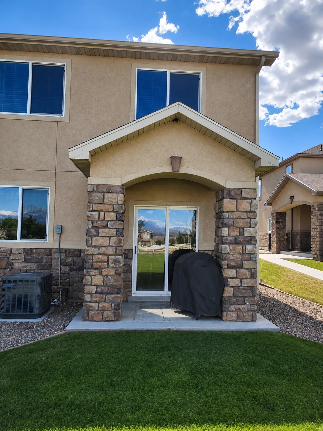 Covered patio featuring stone columns and a concrete slab