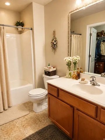 Primary's Built-in bathtub with shower, white vanity with integrated sink, wood-finish cabinetry, and tiled flooring