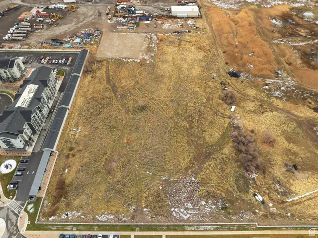 Expansive undeveloped land parcel with surrounding commercial and residential structures