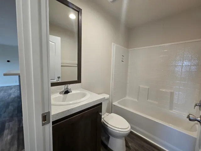 Contemporary bathroom featuring a dark wood vanity with an undermount sink, framed mirror, and an integrated bathtub-shower combination