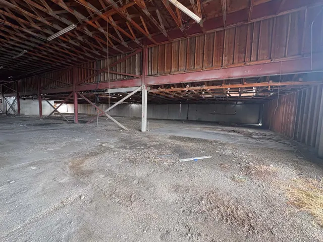 Exposed wood ceiling beams and trusses, metal structural supports, and concrete flooring