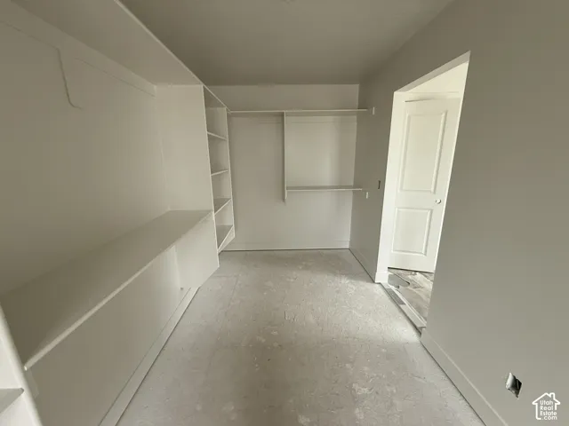 Walk-in storage space featuring built-in shelving units, custom cabinetry, overhead garment rods, and a solid-core interior door