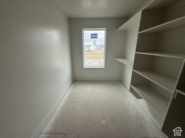 Room with built-in shelving, white-painted walls, and a single-pane window