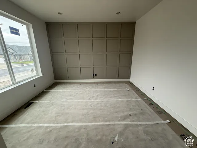 Room interior featuring a grid-patterned accent wall, recessed ceiling lighting, and a large window