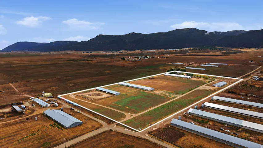 Expansive rural property featuring multiple metal-roofed structures, cleared land areas, and natural terrain