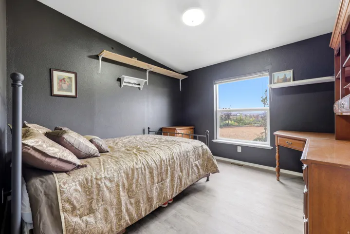 Sloped ceiling with recessed lighting, wood-finish flooring, and a large window
