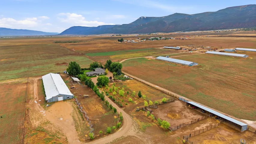 Expansive property featuring multiple outbuildings, fenced enclosures, and substantial acreage with distant mountain scenery