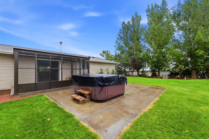 Screened-in patio with direct outdoor access, a concrete patio area, and an adjacent hot tub