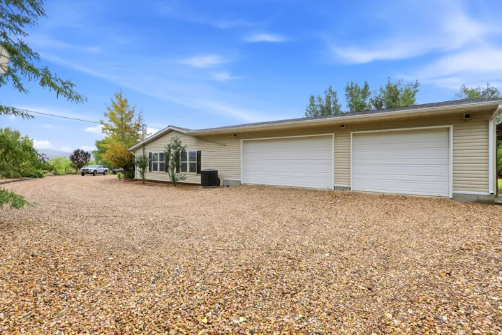 Two-car garage with white doors, light-colored siding, and a gravel driveway