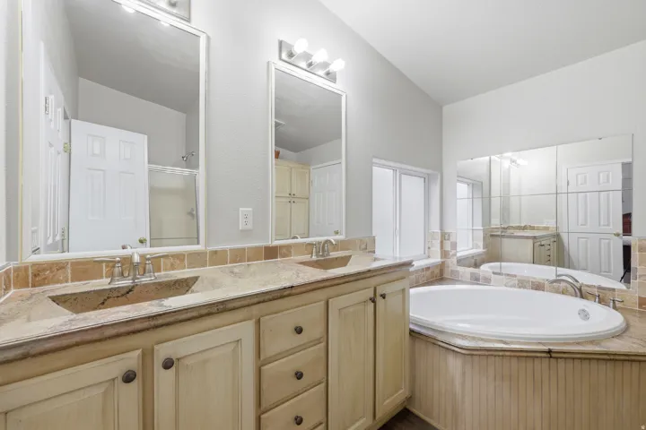 Dual vanity with integrated sinks, stone countertops, and a tiled backsplash