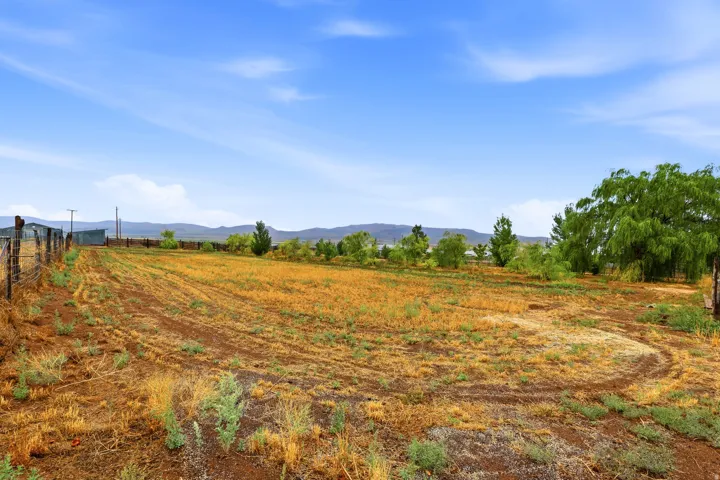 Expansive land parcel featuring a wire fence, natural ground cover, and distant mountains