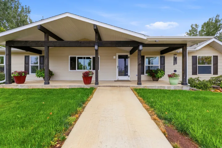 Siding exterior with dark shutters, covered front porch with exposed beams, and a concrete pathway