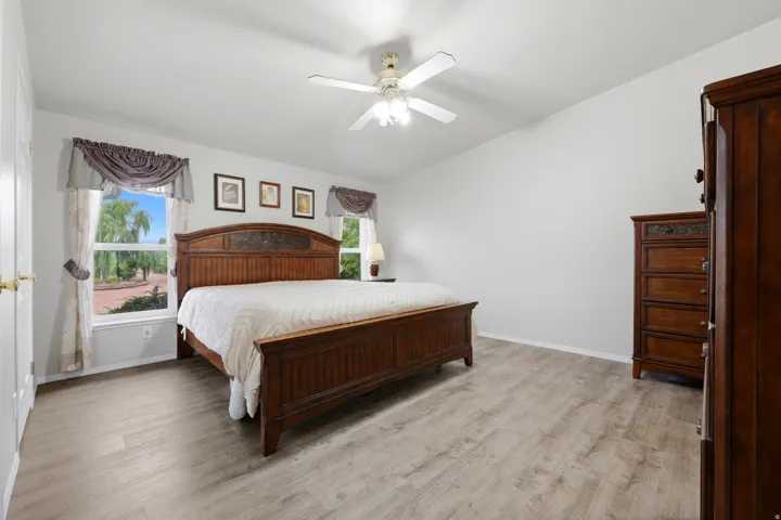 Light wood-finish flooring, white walls, and a ceiling fan with integrated lighting