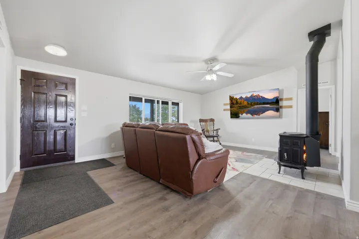 Wood-finish flooring, white ceilings, black paneled entry door, white trim, and a built-in wood-burning stove