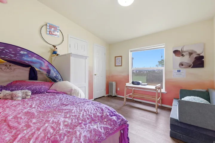 Wood-finish flooring, white trim, and a window with a clear pane