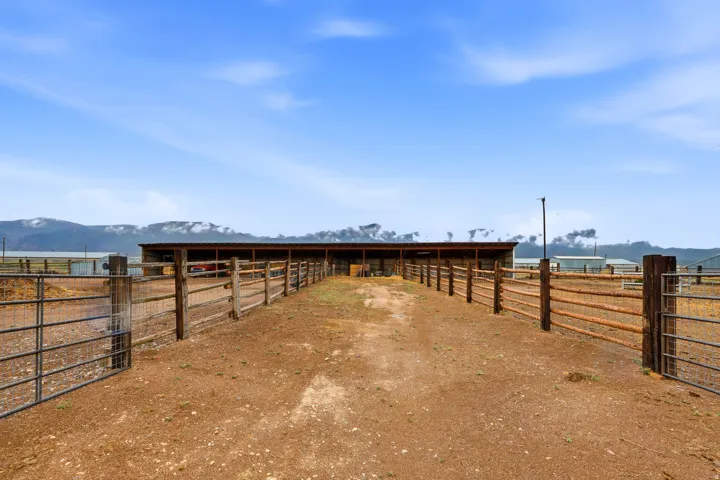 Expansive fenced paddock area featuring multiple gates and a large, covered structure
