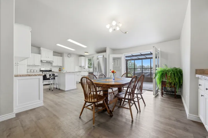 Spacious kitchen featuring white cabinetry, a kitchen island, stainless steel appliances, and wood-finish flooring