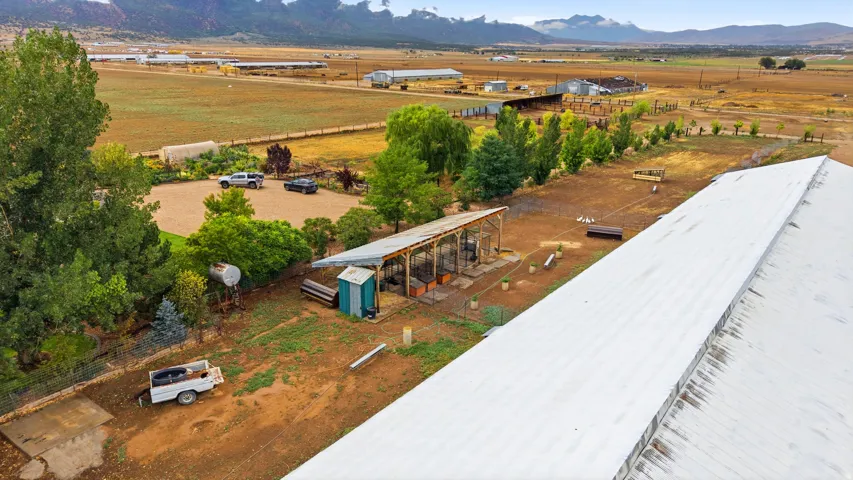Expansive rural property featuring a large barn with a metal roof, open-air outbuilding, and a gravel parking area