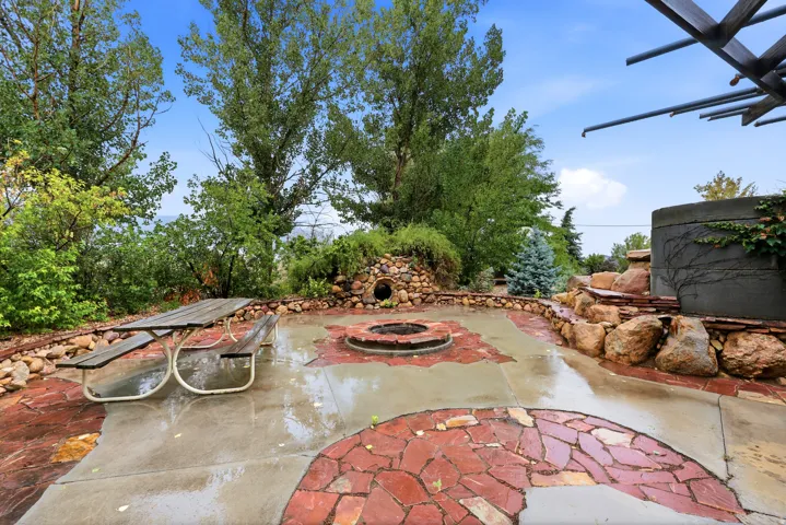 Expansive hardscaping with concrete and flagstone patio, integrated fire pit, and tiered rock landscaping