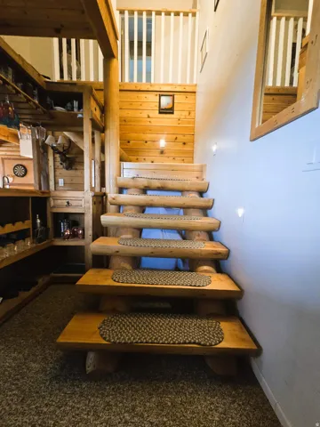 Wood-finish staircase with log-style risers and treads, complemented by a wood-paneled wall
