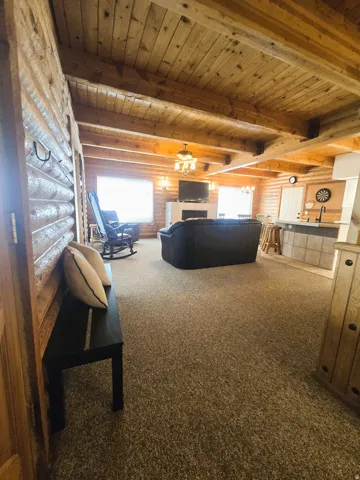 Wood-paneled ceilings with exposed beams, wood-finish walls, and a fireplace with a stone hearth