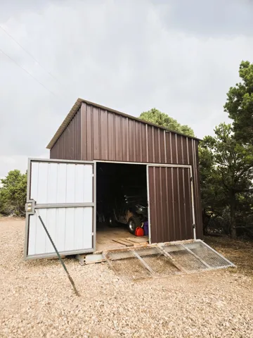 Metal storage building featuring a gable roof, double-door entry, and gravel ground cover