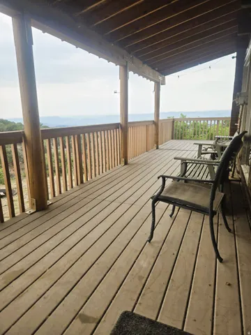 Expansive wooden deck with a wooden railing and a permanent overhead wood-beam covering