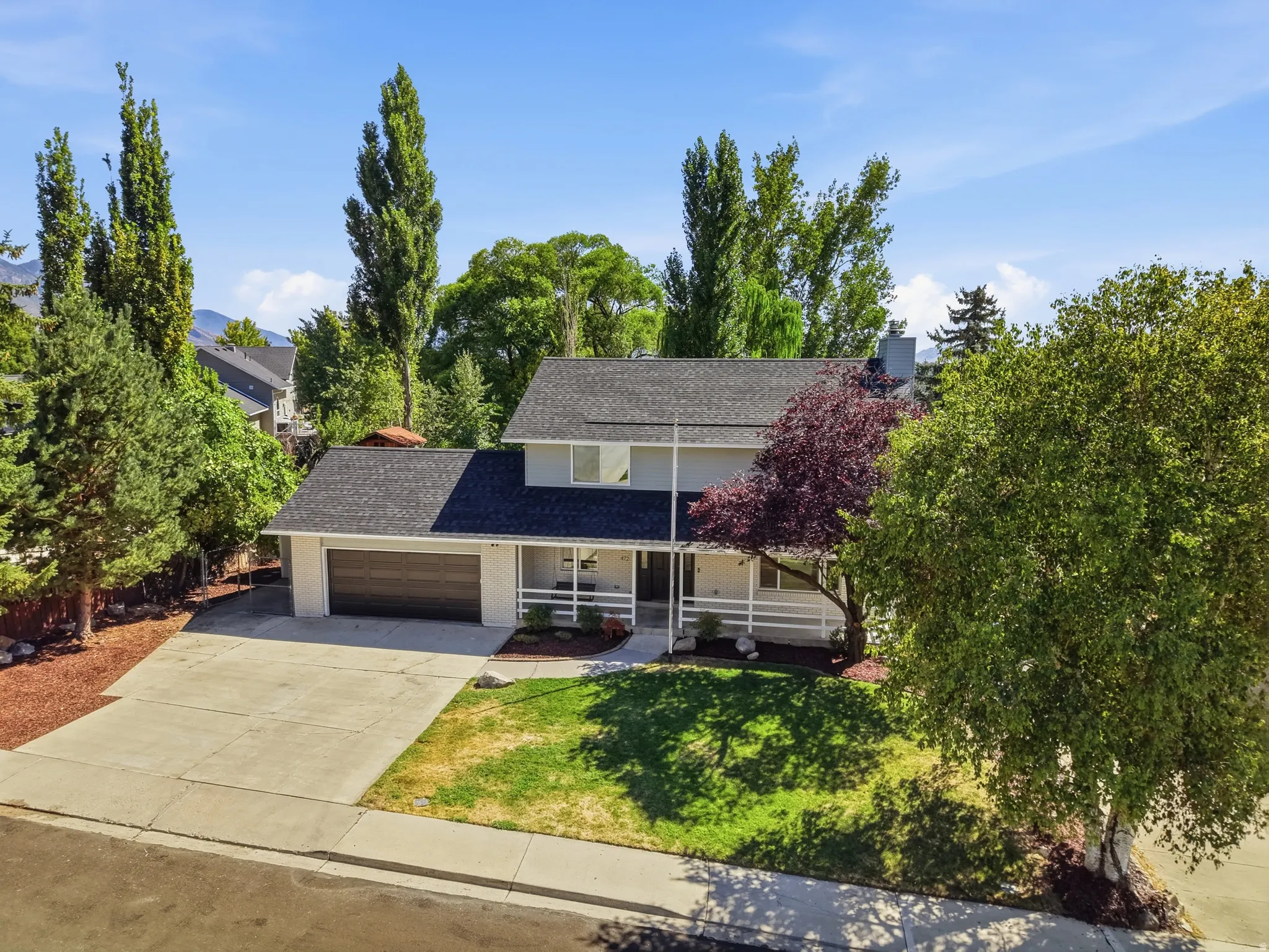 Two-story residence with a dark shingle roof, attached two-car garage, and a concrete driveway