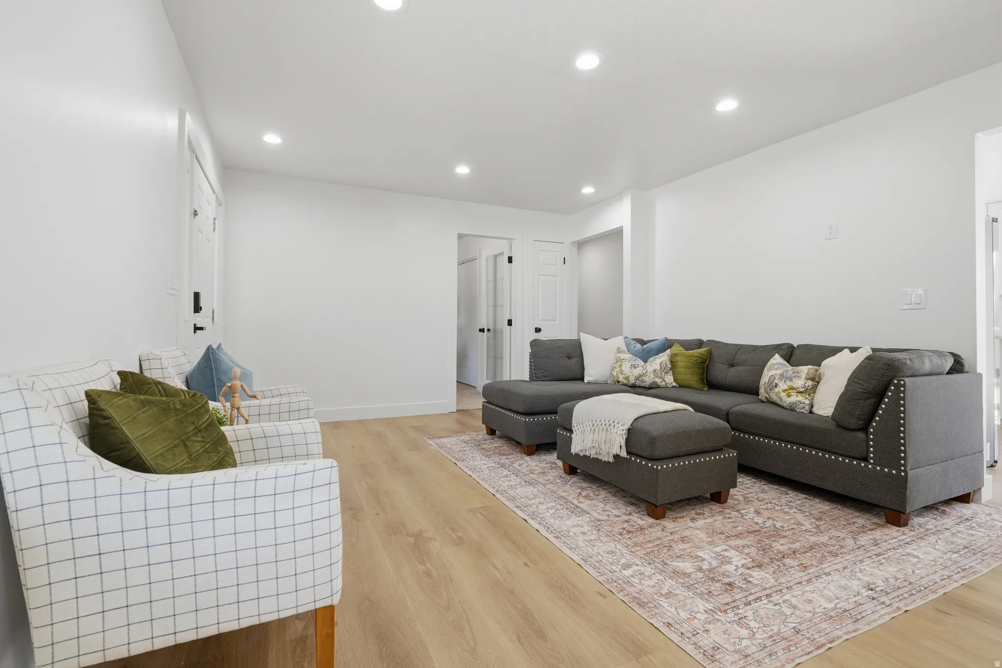 Open living area featuring light wood-finish LVP flooring and recessed lighting